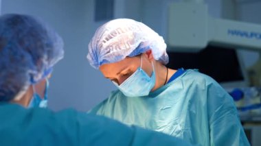 Mavi bornoz, maske ve şapka giymiş kendine güvenen kadın cerrah. Ameliyat yapan bir doktorun portresi.