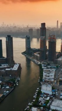 Hudson Nehri New York 'ta akıyor. Akşamları kalabalık bir metropol. Gökyüzünde turuncu bulutlar. Dikey video