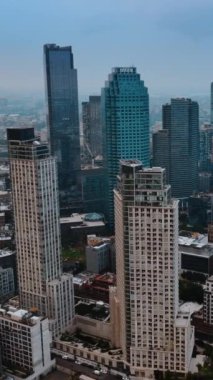 Güçlü gökdelenlerin yanına giden çok sayıda demiryolu var. Gri günde New York manzaralı bir yer. Dikey video