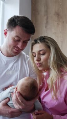 Anne ve baba ve yeni doğan oğulları hastane koğuşunda. Mutlu ebeveynler sevgili bebeklerini öpüyor. Dikey video