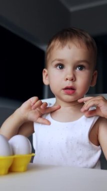 Masada oturan bebek oyuncak yumurtalarla oynuyor. Çocuk kutuyu faiziyle açıp kapatıyor. Dikey video