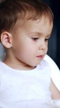 Beyaz, tatlı çocuk yulaf lapası yemeyi reddediyor. Annem ona bir kaşık veriyor ama o yüz çeviriyor. Kapatın. Arkaplan bulanık. Dikey video