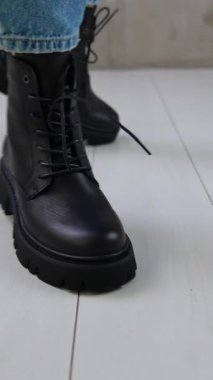 Kot pantolonlu bir model kameraya yaklaşıp arkasını dönüyor. Stüdyoda gösterilen bağcıklı düşük rahat botlar. Kapatın. Dikey video