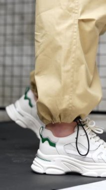 Spor için beyaz şık ayakkabılar. Stüdyoda moda kadın ayakkabıları sunumu. Kapatın. Dikey video