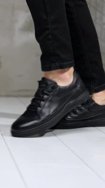 Siyah kotlu ve deri ayakkabılı, ay yürüyüşü yapan tanınmamış bir adam. Stüdyoda şık erkek ayakkabıları gösterisi. Dikey video