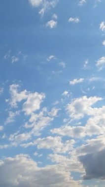 Ufukta parlak beyaz bulutlar uçuşan güneşli mavi gökyüzü. Büyük gri bulut yaklaşıyor ve gökyüzünü kaplıyor. Zaman Uygulaması.