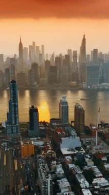 Muhteşem New York şehrinin üzerinde gün batımında inanılmaz turuncu gökyüzü. Nehre bölünmüş gökdelenleri olan bir panorama. Üst görünüm.