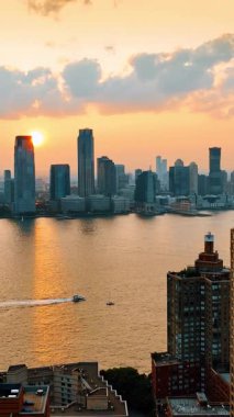 Güzel New York şehir manzarasının üzerinde gün batımı. Tekneler Doğu Nehri 'nden geçiyor. Hava görünümü.