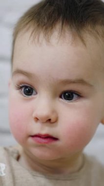 Büyük gri gözleri olan sevimli küçük bebek. Meleklerin beyaz erkek çocuğu bir şeye odaklanmış. Kapat..