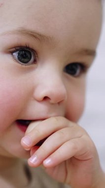 Güzel beyaz çocuk parmaklarını ağzında tutuyor. Bebek parmaklarını çiğnerken başka bir şeye odaklanıyor. Kapat..
