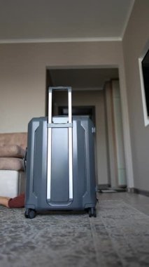 Küçük çocuk yerde sürünüyor ve bavulun arkasına saklanıyor. Sevimli bebek saklambaç oynuyor ve kameraya doğru sürünüyor. Kara kedi arka planda. Dikey video.