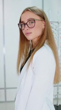 Müşteri optikte gözlük seçiyor. Gözlükçüden gözlük takan ve alan bir kadın.