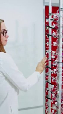 Bir çift gözlük seçen bir bayan. Optik dükkanında gözlük takan güzel bir genç kadının portresi.