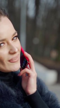 Kadın telefonda konuşuyor. Parkta cep telefonuyla konuşan çekici bir kadın.