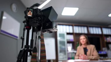 Tripodun görüntülerini gösteren profesyonel bir kamera. Bir kadın. Düşük açı. Kadın blogcu blogu veya vlog 'u için içerik oluşturur. Bulanık arkaplan.