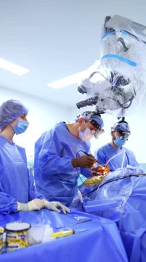 Tıbbi ekip ameliyathanede çalışıyor. Dikkatli bir cerrah modern cerrahi aletler kullanır. Dikey video.