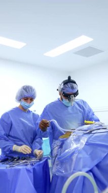 Cerrah, yardımcı ameliyat hemşiresine kullanılmış bir alet verir. Kadın doktor, doktor için metal enstrüman hazırlıyor. Dikey video.