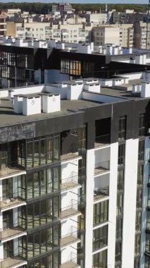 Şehirde yeni bir mimari. Yolun yakınındaki yüksek katlı apartmanlar. Çok katlı binanın modern tasarımı. İHA uçuşu. Dikey video