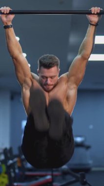 Üstsüz adam direkte antrenman yapıyor. Spor salonunda bacaklarını sıkarak egzersiz yapan profesyonel bir sporcunun portresi. Her gün egzersiz rutini. Dikey video