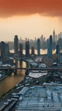 Havadan bakıldığında New York 'un canlı bir şehri. Metropolün üstündeki gökyüzünde pembe bulutlar. Nehrin üzerinde yükselen gökdelenler. Dikey video