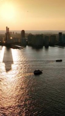 Nehrin üzerinde duran ve suya yansıyan gökdelenlerin siluetleri. Altın saatinde New York silueti. Üst Manzara. Dikey video