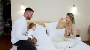 Mutlu ebeveynler, güzel erkek çocuklarıyla yatak odasında oynarlar. Baba, çocuğunu annesine atar ve onun başının üstünde bir çocuk büyütür..