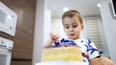 Sevimli çocuk yemeğini dikkatlice çiğniyor. Alçak açılı bebek jöleli büyük bir pasta yiyor..