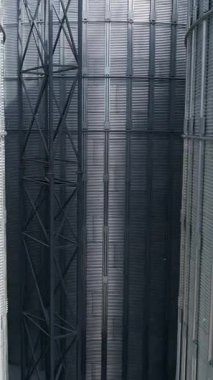 Büyük metal ambarlarının dışı. Ekin saklamak için gümüş asansörler. Modern hangar binaları. Tarım depolama tankları. İnsansız hava aracı görüntüsü. Dikey video
