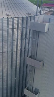 Tahıl asansörleri devrede. Duman içinde büyük metal ambarları. Modern endüstriyel bir fabrikanın gümüş alüminyum kapları. Hava görüntüsü. Dikey video