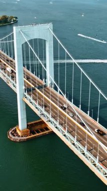 Bronx, New York 'a gidip gelen arabalar. Güneşli bir günde Throgs Boyun Köprüsü 'nün hava görüntüsü. Tekneler arka planda East River 'da yelken açıyor. Dikey video