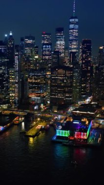 New York 'un birçok rıhtımından birine yaklaşıyoruz. Neon ışıkları nehrin yukarısından geliyor. İnanılmaz gökdelenler arka planda gökdelenler. Dikey video