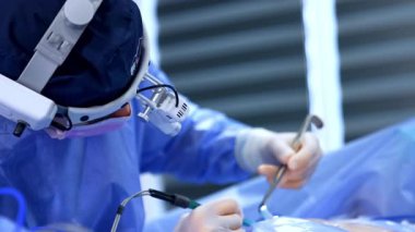 Farlar takan doktor alet aletlerini kullanarak hastanın üzerine eğildi. Göğüs büyütme ameliyatının başarısı. Kapat..