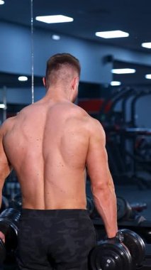 Kas kasları için egzersiz. Atletik adam dambılla çalışıyor.
