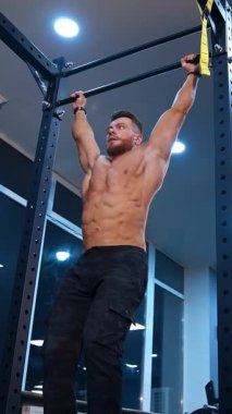 Güçlü bir atlet barfiks çekiyor. Spor salonundaki yatay çubukta egzersiz yapan kaslı adam.