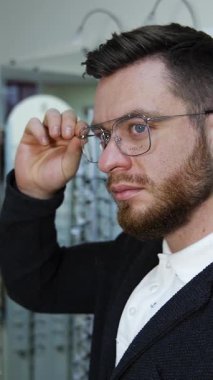 Optik mağazada gözlük seçen bir adam. Optik dükkanında gözlük takan genç bir adam.