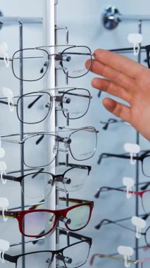 Optik mağazada gözlük seçen bir adam. Optik mağazada gözlük çerçevesi seçen yakışıklı genç adam.
