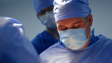 Şapkalı ve maskeli tombul beyaz cerrah operasyonda çalışıyor. Nöroşirürjide asistanlık yapan bir doktor portresi..