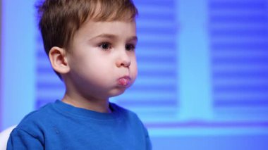 Küçük çocuk süt ürünlerini ağzında tutuyor. Küçük çocuk bir şeyi işaret ediyor. Küçük çocuk şişeden süt içti. Portreyi kapat.