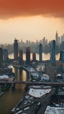 New York 'ta gökyüzünü kaplayan turuncu bulutlar. Metropolis 'te gün batımı. Arkaplanda gökdelenler. Dikey video