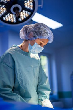 Steril bölgede ameliyat yapan bir cerrah. Bir tıp uzmanı titizlikle parlak, steril bir ameliyathanede ameliyat yapar ve elimizdeki işe odaklanır..