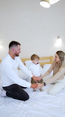 Kafkasyalı mutlu anne babalar küçük oğullarıyla oynuyorlar. Anne ve baba, gülen oğullarına emzik yutturuyorlar. Dikey video.