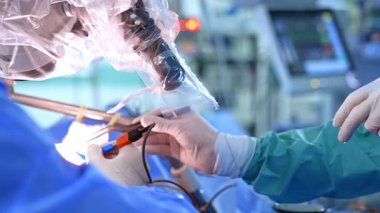 Lateks eldivenli doktorların elleri metal aletler ve cerrahi aletler kullanıyor. Beyin cerrahisi mikroskop altında. Kapat..