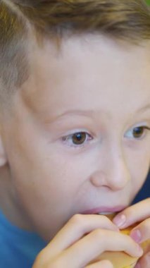 Fast food restoranında lezzetli hamburger yiyen genç bir kız. Zararlı beslenme Dikey video