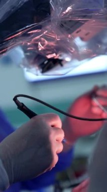Cerrahın eldivenli ellerinde elektrikli alet. Bir ilaç şırıngadan ameliyat yerine püskürtülür. Dikey video.