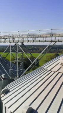 Ekinleri depolamak için büyük çelik kuleler. Kapalı depo ve siloları olan tahıl terminalinin havadan görüntüsü. Dikey video