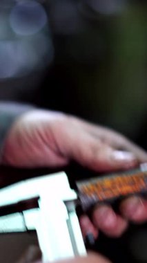 Vernier Caliper ile Endüstriyel İşçi. Fabrika işçisi atölyedeki kalibreli çelik detaylarını ölçüyor. Dikey video