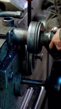 Metal imalatı endüstrisi. El yapımı ağır endüstriyel işçiler, makinede mekanik dönüşler yaparak metal fabrikası işlemleri üzerinde çalışıyorlar. Dikey video