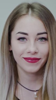 Mutlu, genç bir kadın. Neşeli bir şekilde gülümseyen güzel bir genç kadının kapalı bir portresi. Dikey video