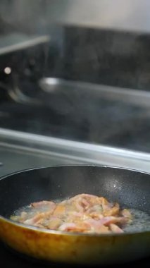 Restoran mutfağında kızartma tavası. Restoranın mutfağında yemek pişiren profesyonel bir aşçı. Dikey video