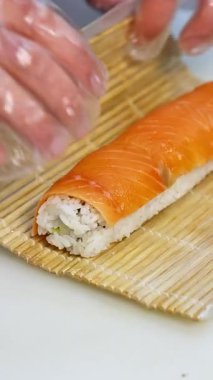 Şefin elleri Japon yemeği hazırlıyor. Lokantada suşi hazırlama manzarası. Dikey video